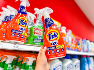hand holding a bottle of tide laundry stain remover in front a target shelf