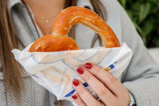 a person holding up an auntie annes pretzel 