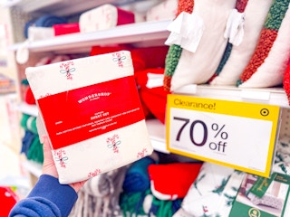 hand holding a holiday sheet set in front of 70% off Target clearance