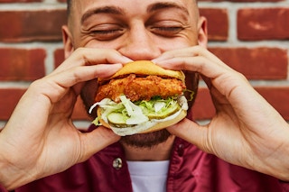 a person eating a shake shack chicken sandwich