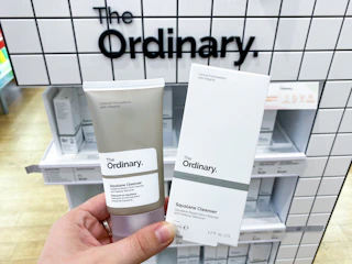 a hand holding a skincare product in front of a display