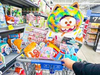 hand pushing assorted toys in walmart cart