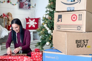 a woman wrapping gifts by a huge stack of online order boxes