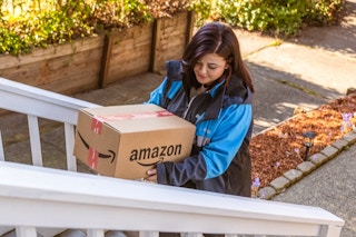 an amazon delivery driver walking up stair with a package 
