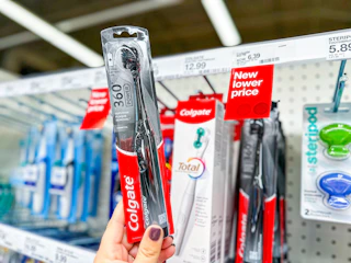 hand holding a colgate 360 electric toothbrush in front of a target shelf