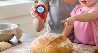 a person using a thermometer in a loaf of bread