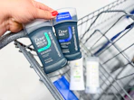 hand holding two dove deodorants over walmart shopping cart