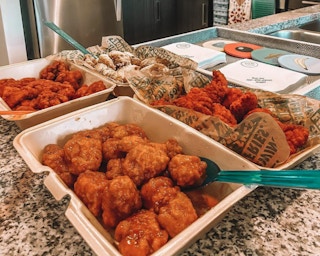 Containers of boneless chicken wings sitting on a counter.